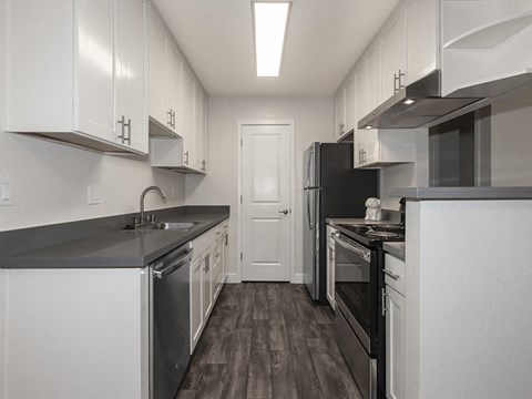 an all white kitchen with stainless steel appliances and white cabinets